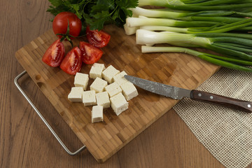 organic cheese cubes and tomatoes on wooden table top view