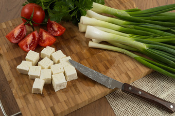 organic cheese cubes and tomatoes on wooden table top view