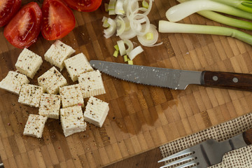 organic cheese cubes and tomatoes on wooden table top view