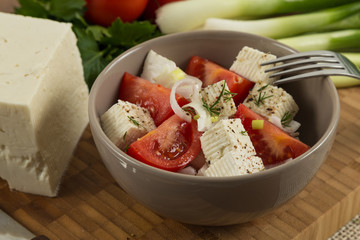 tomatoes and cheese salad with vegetables on wooden background