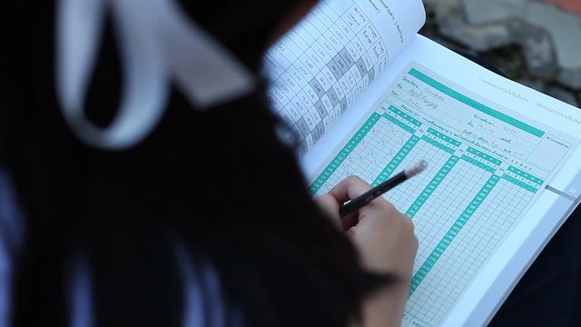 The Girl hand is filling a blank on answer paper with pencil