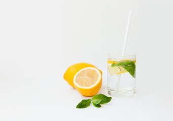 Homemade lemonade with water, lemon and mint leaves in a glass on a white background.