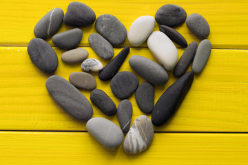 Fototapeta na wymiar heart made of sea pebbles on a bright yellow background