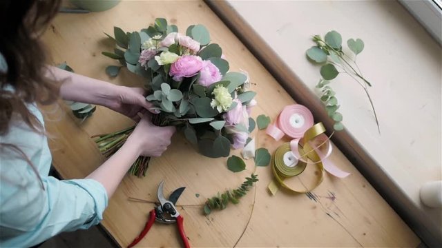 Top View of Female florist making beautiful bouquet at flower shop, peone and rose flower composition for wedding