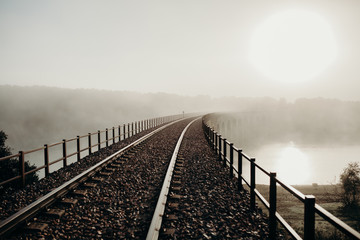 Railway bridge over a river in a foggy day.