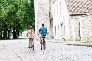 Happy traveling couple riding on bicycles. Boyfriend and girlfriend in old town. Love, relationship, romance concept.