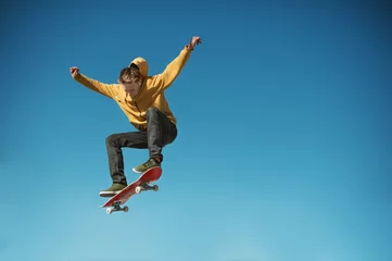  A teenager skateboarder does an ollie trick on background of blue sky gradient © yanik88