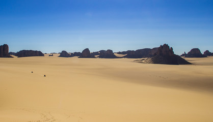 Fototapeta na wymiar Cars passing through a desert plateau in South Algerian Desert -Tassili N'ajjer