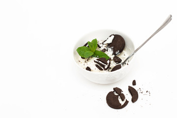 The view from the top. Homemade vanilla ice cream in a white Cup with crushed chocolate cookies and mint on a white background.