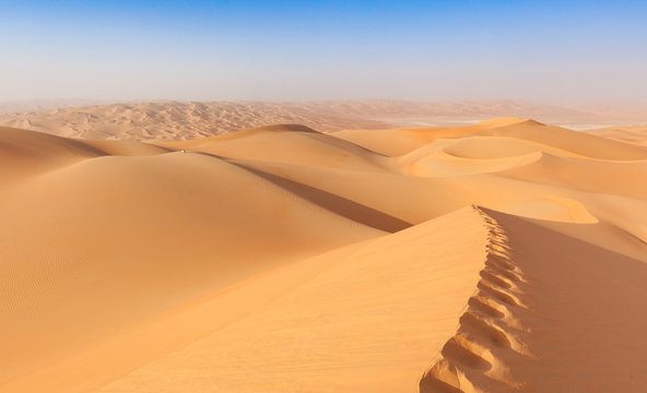arab man in traditional outfit sitting over a Dune in arabian Desert