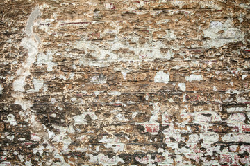 Cracked plaster on the brickwall, grunge background of brown bricks