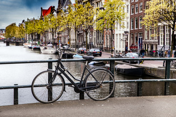 Fototapeta premium Black bicycle on the bridge on the canal of Amsterdam, Netherlands