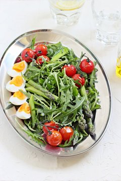 
    Asparagus salad with arugula, cherry tomatoes and eggs. Overhead view. 