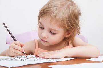 Little girl drawing with colored pencils on paper