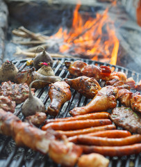 BBQ Chicken Legs and pork meat Roasted On The Hot Flaming Charcoal Grill