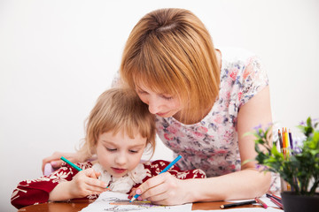 Young mom and her little daughter drawing