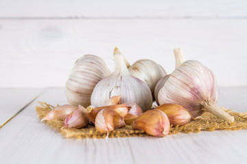 Garlic cloves and garlic bulb on a white wooden table.