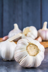Garlic cloves and garlic bulb on a wooden board on a gray background.