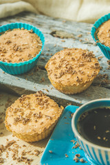 Chocolate muffin with soft cream and fresh blueberry powdered with sugar, cup of coffee, rustic background