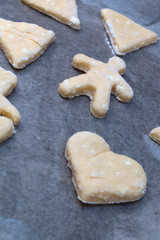 Cookie dough in different shapes lies on the baking sheet.