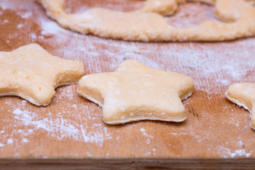Cookie dough in different shapes lies on the baking sheet.