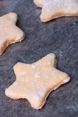 Cookie dough in different shapes lies on the baking sheet.