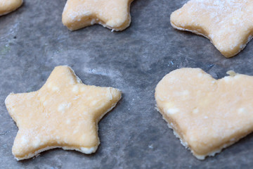 Cookie dough in different shapes lies on the baking sheet.