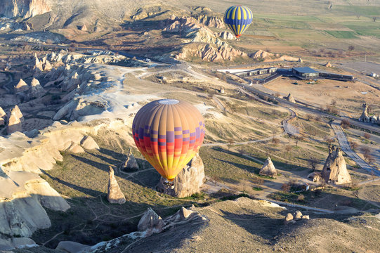 Many balloons over the extraordinary rocks formations rock hills of mushroom valley, pasabaglari, Cappadocia, Nevsehir, Turkey.
