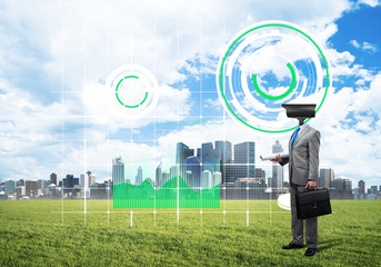 Camera headed man standing on green grass against modern cityscape