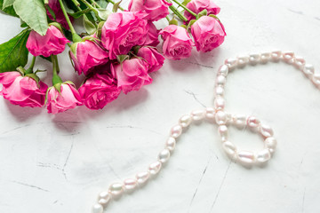roses and necklace on white table background