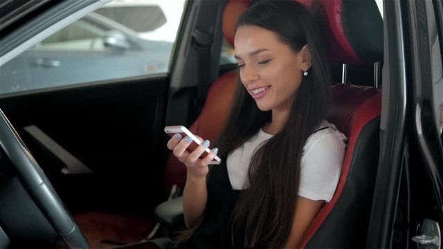 Happy brunette woman student in modern business class car with phone use applications for travellers