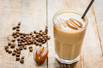 coffee break with cold iced latte and beans on wooden table background