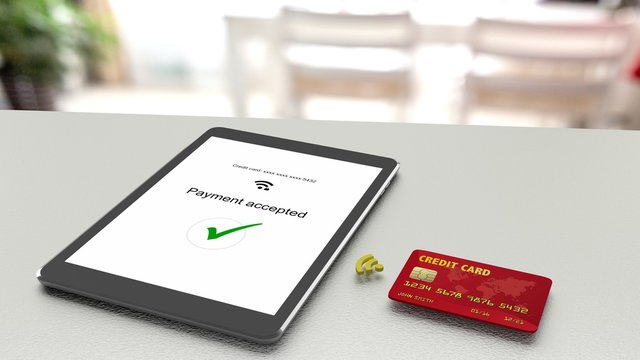 Tablet on table accepting a wireless payment from a credit card