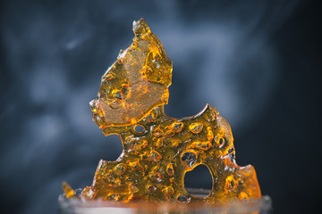 Piece of cannabis oil concentrate aka shatter with smoke