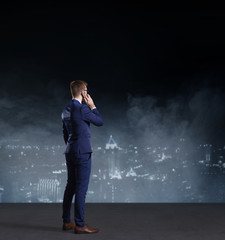 Businessman with smartphone standing on a night city background.  Job, business, career, concept.