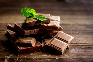 black and milk chocolate bars with mint dark wooden table background