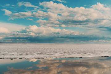 Obraz premium Scenery view of frozen sea during ice drift on springtime with dramatic teal sky and clouds having reflections in melt water on evening in Novosibirsk, Russia