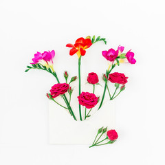 Pink and red freesia, roses and vintage paper envelope isolated on white background, Flat lay, Top view