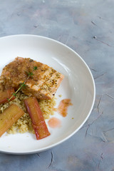 Grilled salmon with quinoa and rhubarb sauce. Gray background, white plate. Isolated.