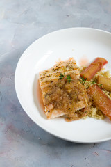 Grilled salmon with quinoa and rhubarb sauce. Gray background, white plate. Isolated.