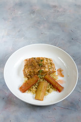 Grilled salmon with quinoa and rhubarb sauce. Gray background, white plate. Isolated.
