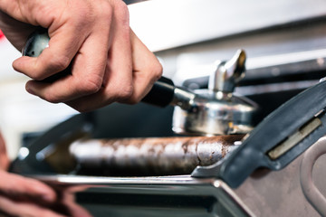 Close-up of hand throwing used coffee ground into a metallic container