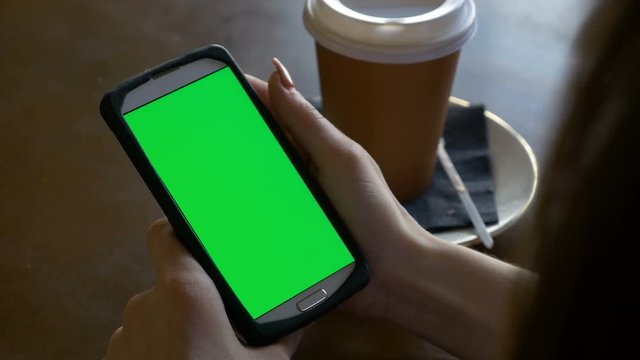 Student girl studies using smart phone in portrait mode with coffee on the table