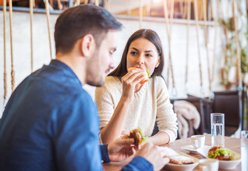Beautiful young couple sitting in a cafe, having breakfast. Love, food, lifestyle
