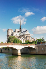 Fototapeta na wymiar Notre Dame cathedral at summer day with bridge over Seine river, Paris, France