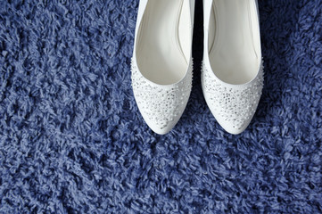 Beautiful white female shoes on a blue carpet