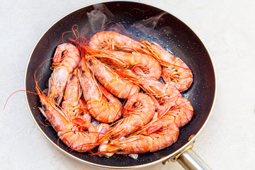 Large orange shrimp stir-fried in a skillet with garlic.