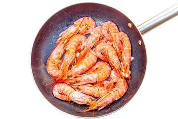 Large orange shrimp stir-fried in a skillet with garlic.