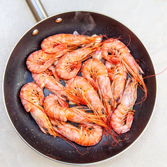 Large orange shrimp stir-fried in a skillet with garlic.