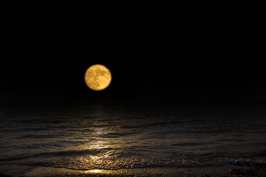 Full moon over the sea. Astronomy shot of the planets and the starry sky. The scene with the round moon. The mystical nature time.